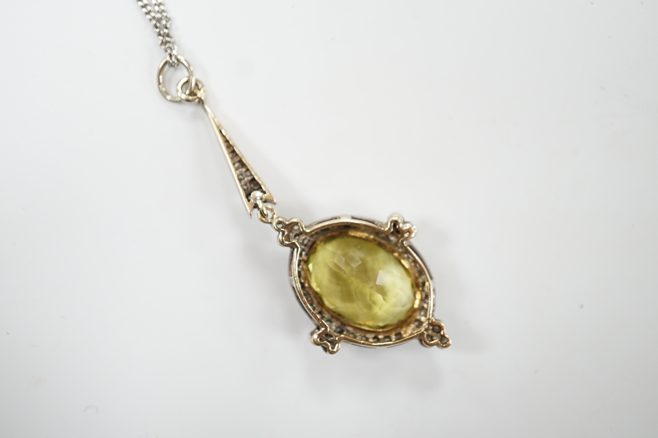 A late Victorian yellow metal and single stone oval cut citrine set drop pendant, with diamond set border and bale, 53mm, on a later 375 white metal chain, 50cm, gross weight 11.2 grams. Good condition.